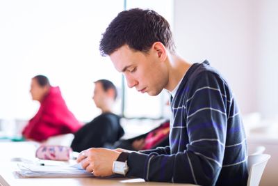 young, handsome male college student sitting in a...