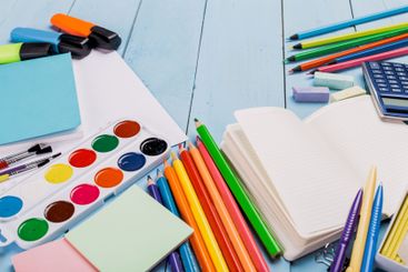 Colorful stationery and art supplies arranged on a light...