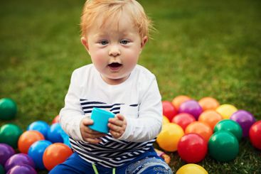 Portrait, colourful balls and baby in backyard, relax...