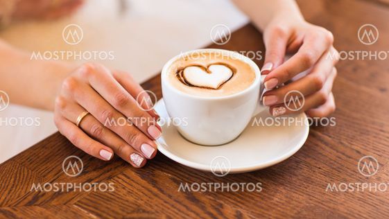 woman holding hot cup of coffee, with heart shape