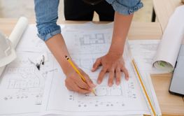 Young architect sketching house plans on a work desk in a...