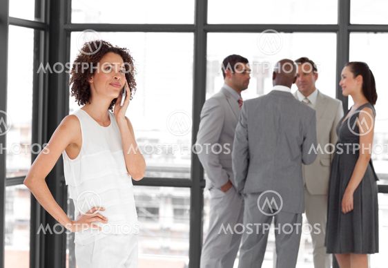 Beautiful Businesswoman holding a phone at workplace with his colleagues