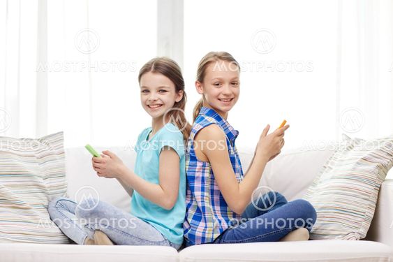 happy girls with smartphones sitting on sofa