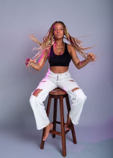 Brunette model with braids in her hair, wearing white...