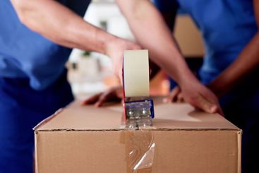 Professional Movers Pack Cardboard Boxes With Tape to...