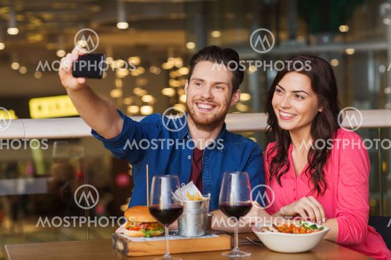 couple taking selfie by smartphone at restaurant