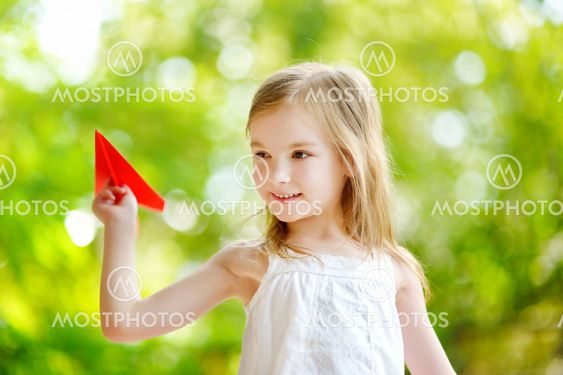 Adorable little girl holding a paper plane