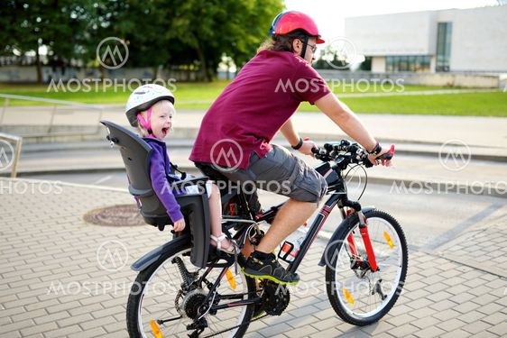 Happy father and his little toddler daughter rinid a bike...