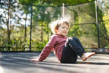 Little boy jumping on a trampoline in a backyard on warm...