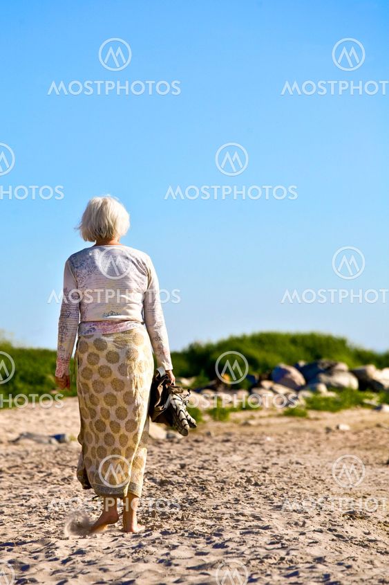 Promenerande kvinna på stranden. Foto: Mujo