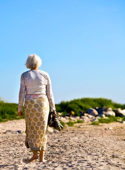 Promenerande kvinna på stranden. Foto: Mujo