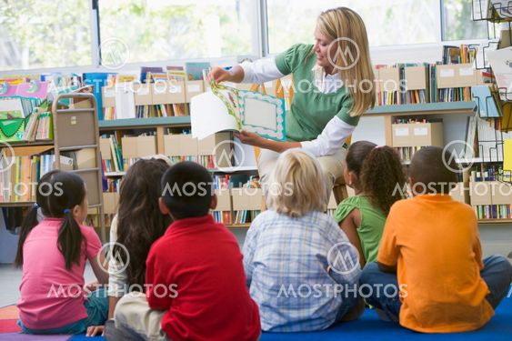Kindergarten teacher reading to children in library