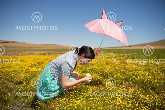 Beautiful adult smelling flowers on sunny field enjoying herself
