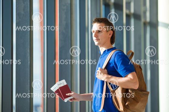 Young man holding passports and boarding pass at airport