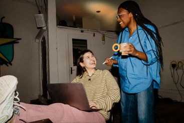 Happy female entrepreneur with female colleague holding...