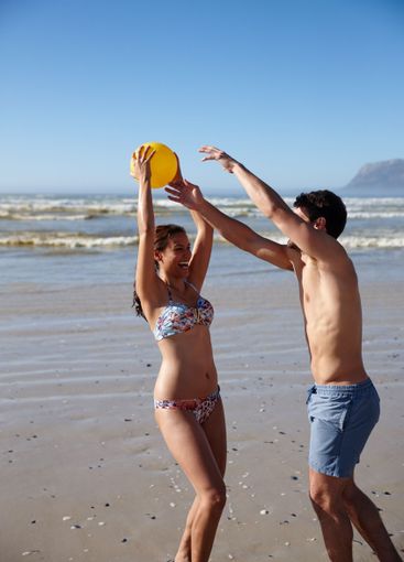 Happy couple, beach and playing game with ball for fun...