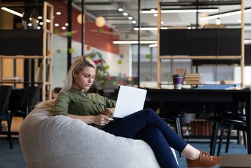 Caucasian businesswoman using laptop sitting in armchair...
