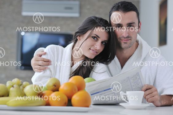 Happy couple reading the newspaper in the kitchen at breakfast