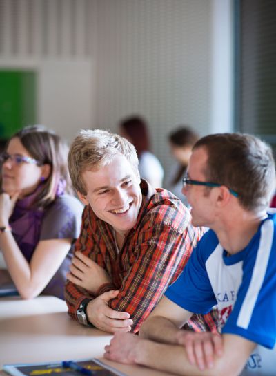 Handsome college student sitting in a classroom full of...