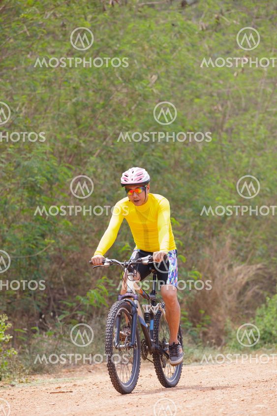 young man riding mountain bike in dusty road use for sport leisure and healthy activities