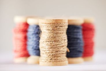 Many rolls of coloured yarn or string lined up in a row...