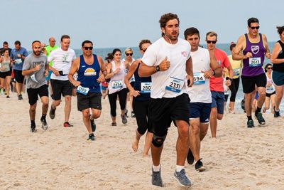 Many runners racing on the sand at the beach