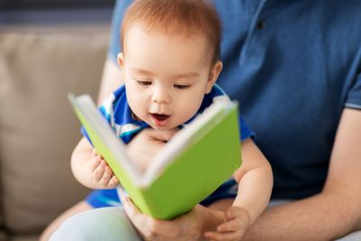 close up of baby boy and father with book at home