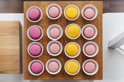 Multicoloured macaroon in cups served on wooden tray