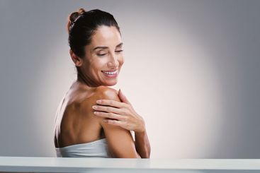 Happy, woman and shoulder skincare in studio for...