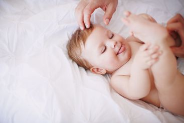 Hands, parent and baby with playing on bed for child...