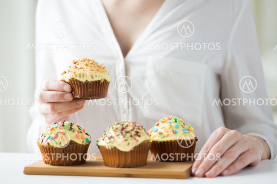 close up of woman with glazed cupcakes or muffins