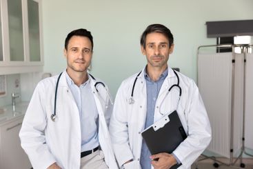 Two confident male doctor colleagues with stethoscopes...