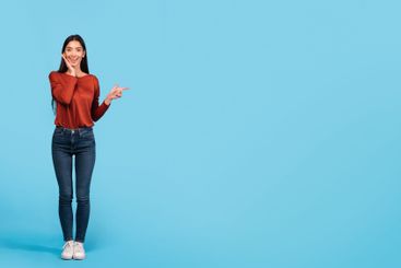 Brunette woman in casual outfit pointing against bright...