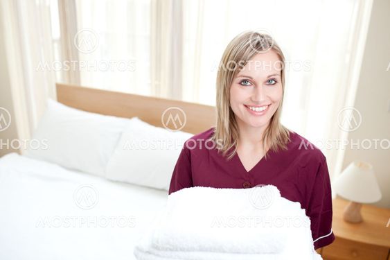 Radiant cleaning lady holding towels in a hotel room