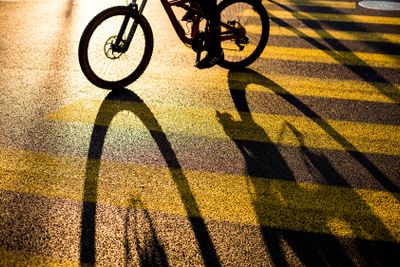 Biker/Cyclist on a crossing in a city casting a long shadow