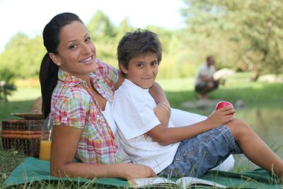 a mother and her son at picnic, the father is fishing