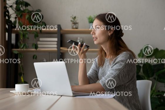 Confident businesswoman recording audio message, sitting...