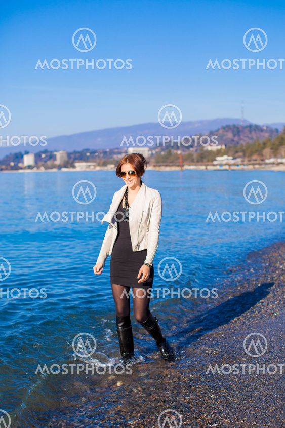 Beautiful young woman walking on the beach in winter sunny day alone