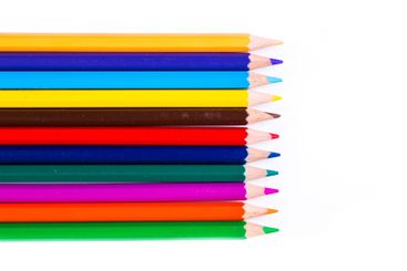 Vibrant colored pencils arranged neatly on a white...