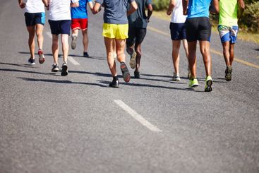 Athlete, legs and group running in road for marathon...