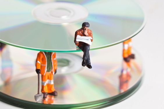 Miniature people in action with CDs