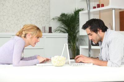 young couple sitting face to face with laptop