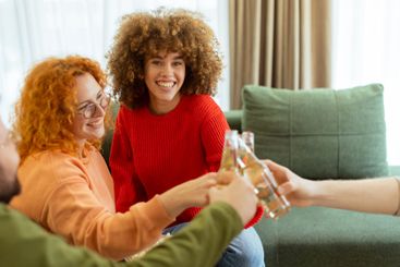 Friends celebrate together in a cozy living room,...