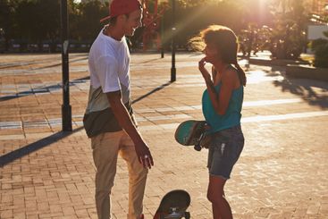 Friends, skateboard and sunset in street, city or...