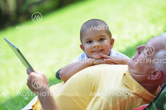 grandfather and child in park using tablet