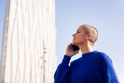 woman with buzz cut talking happy on mobile phone