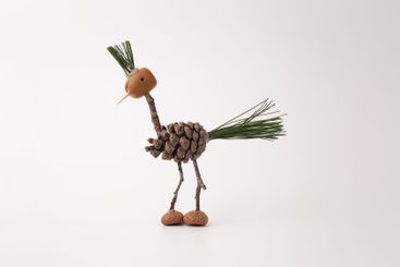 A handmade bird crafted from pine cones and twigs, on a...