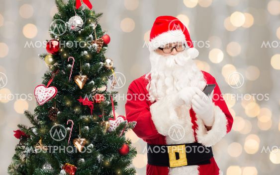 santa claus with smartphone and christmas tree