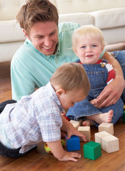 Father And Sons Playing With Coloured Blocks At Home