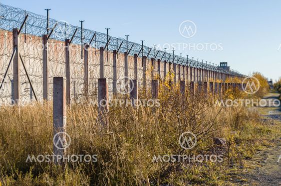 Prison wall and sharp wire barbs coiled